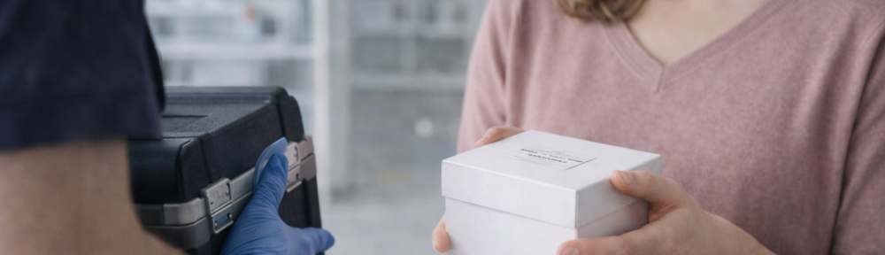 Kobieta po poronieniu przekazująca zabezpieczoną próbkę do badań genetycznych kurierowi w szpitalnym korytarzu.