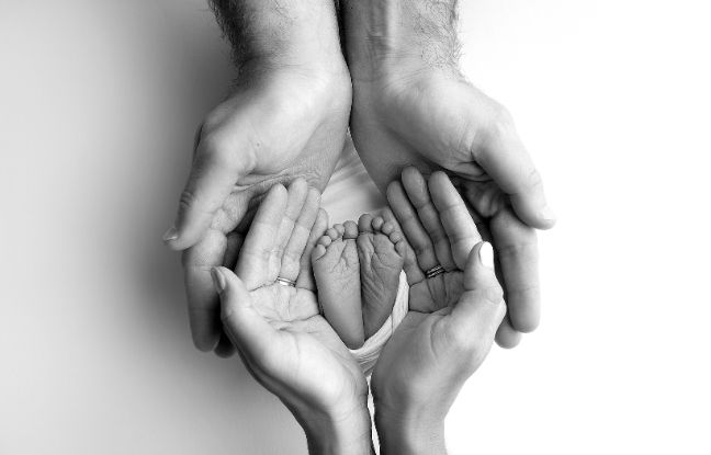 wasze historie po poronieniu - rodzice trzymający w słoni stópki niemowlaka